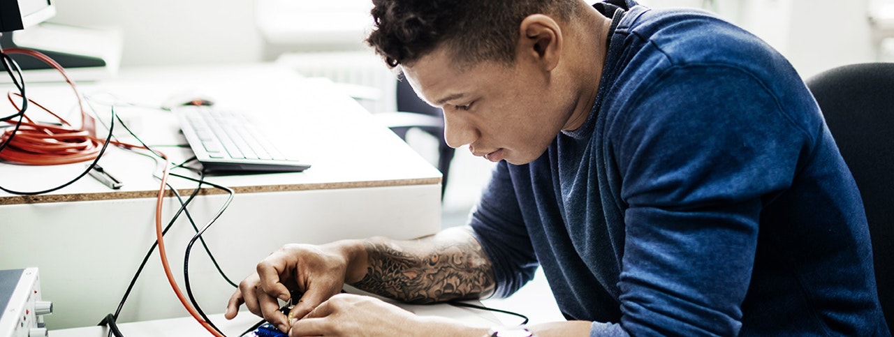 An engineering student working on a project at university, focussing on a electrical circuit.