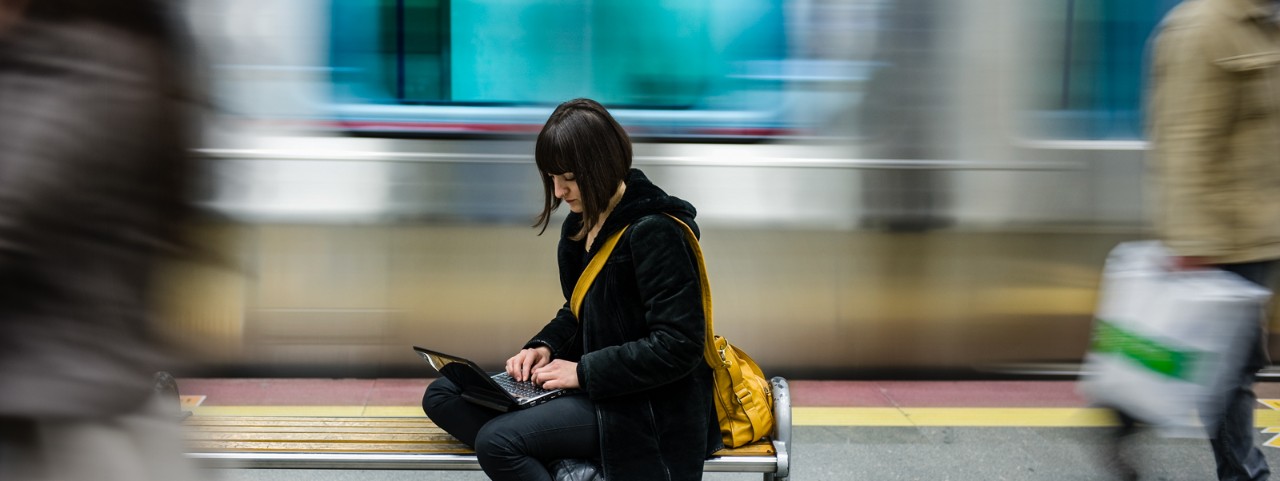 Subway Train Series: Beautiful young woman looking at computer while waiting for subway train