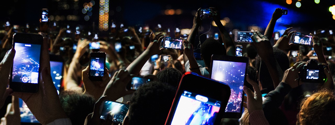 Crowd of people recording video with cell phones at night