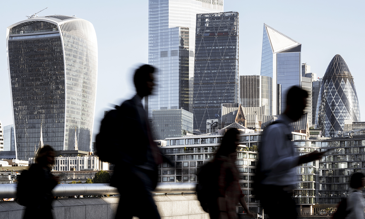 UK, London, blurred motion of incidental business people walking to work with view of the financial district behind
