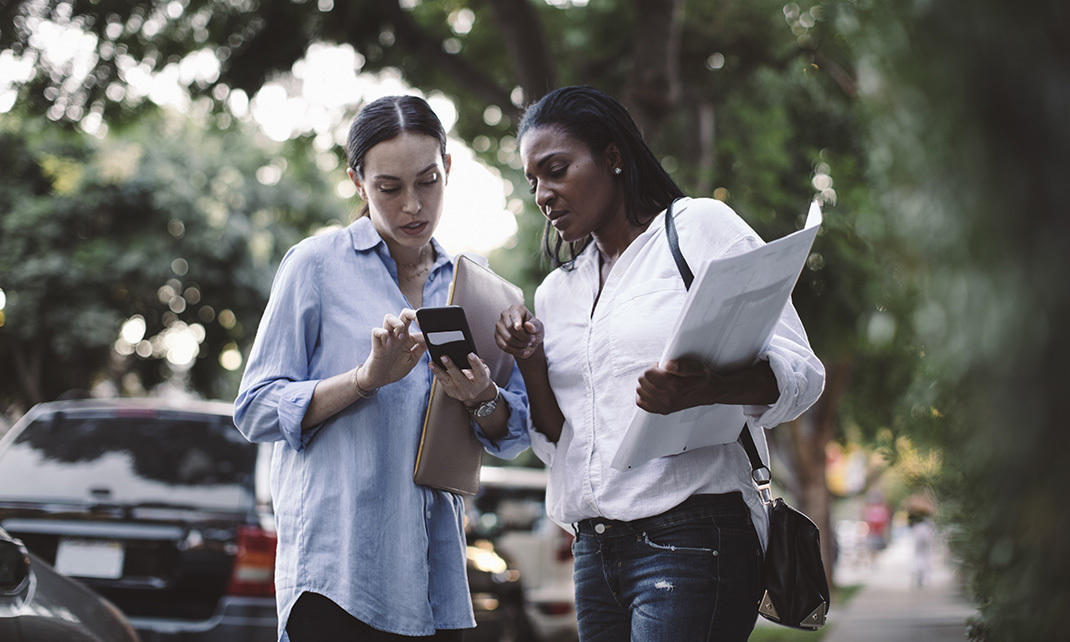 YOUNG WOMAN USING PHONE WHILE STANDING ON CAR