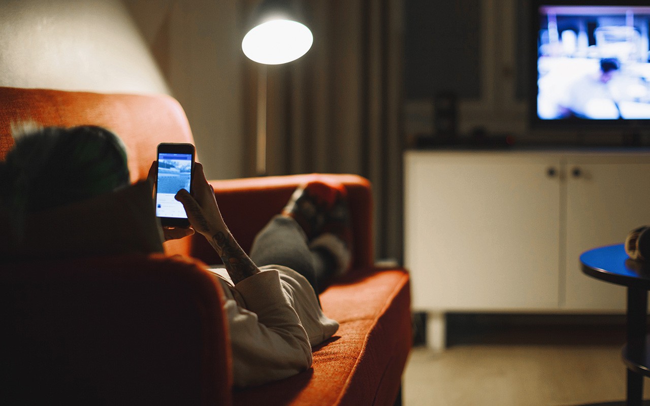 Young woman relaxing with smartphone on sofa