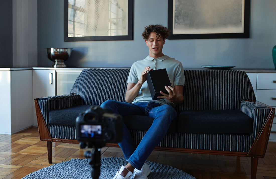 A young man unboxing a product in front of a camera.